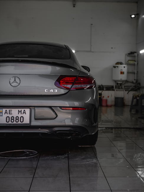 A sleek Mercedes-Benz C43 coupe inside a car wash, showcasing its polished taillight and wet surface.